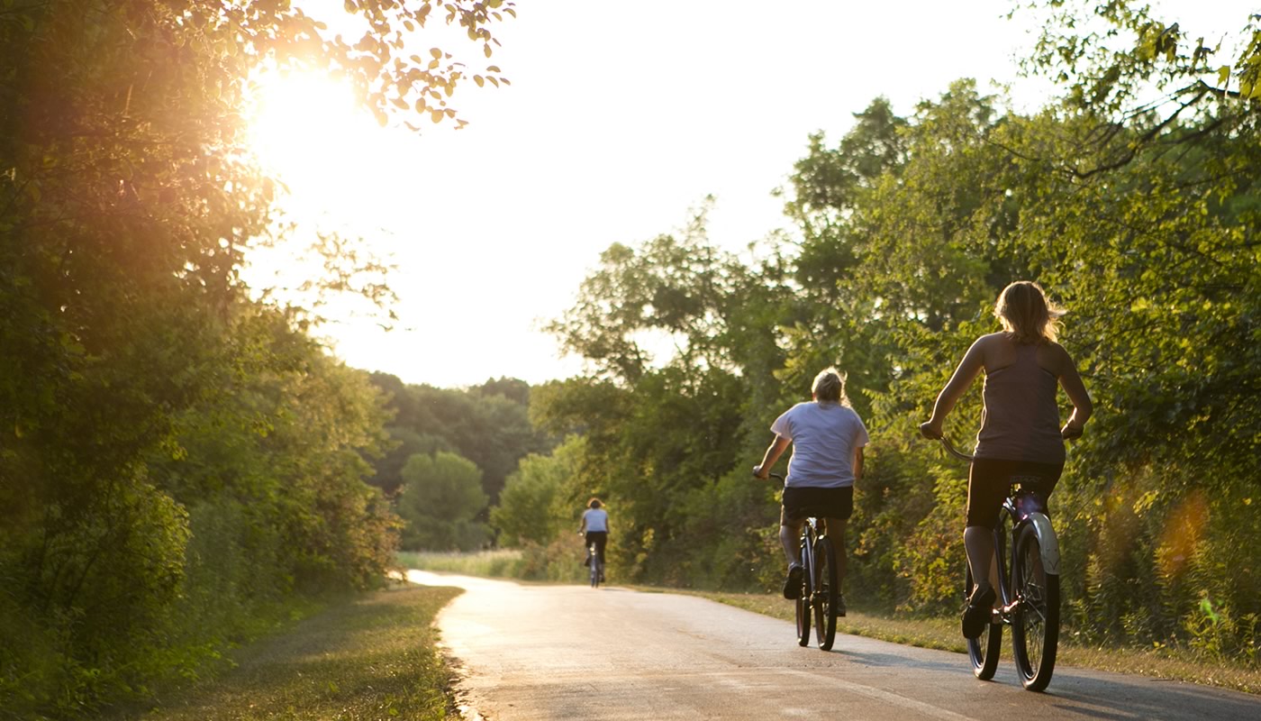 Three people riding bikes at sunset