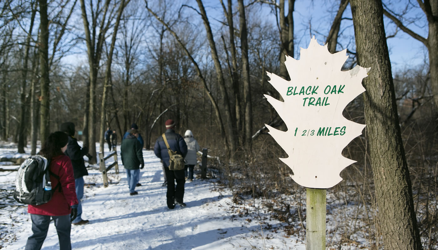a trail sign with people in the background at Little Red Schoolhouse Nature Center