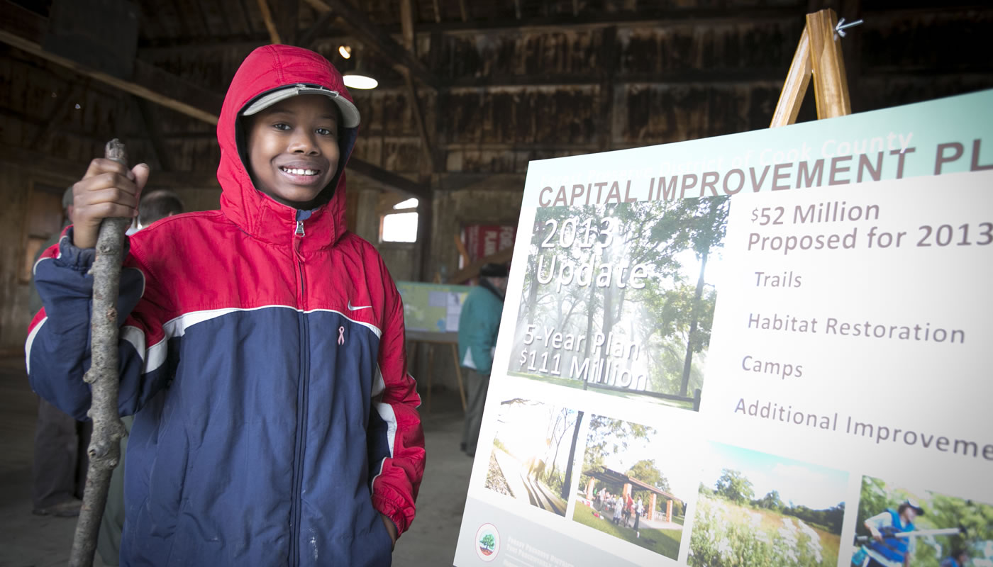 a person poses next to a poster with details of the Forest Preserves Camping Master Plan