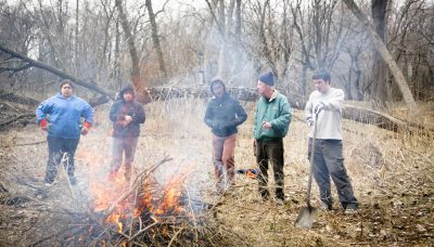 five volunteers standing near a fire at Eggers Grove