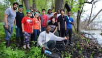 a group of volunteers posing near wetland plants they just finished planting