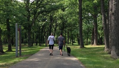 two people walking a dog on the Tinley Creek Trail at Yankee Woods