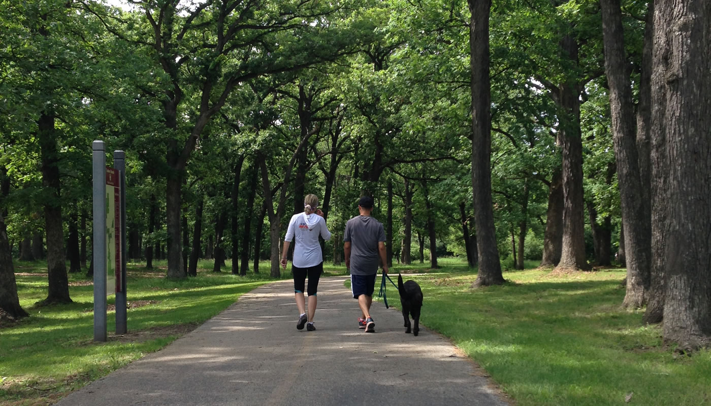 two people walking a dog on the Tinley Creek Trail at Yankee Woods
