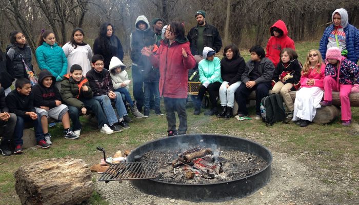 A Forest Preserves staff member showing how to light a fire in front of a group at a Camping 101 event.