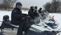 four people on snowmobiles