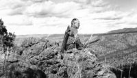 Aldo Leopold sitting on a rock and looking into a valley at Rio Gavilan