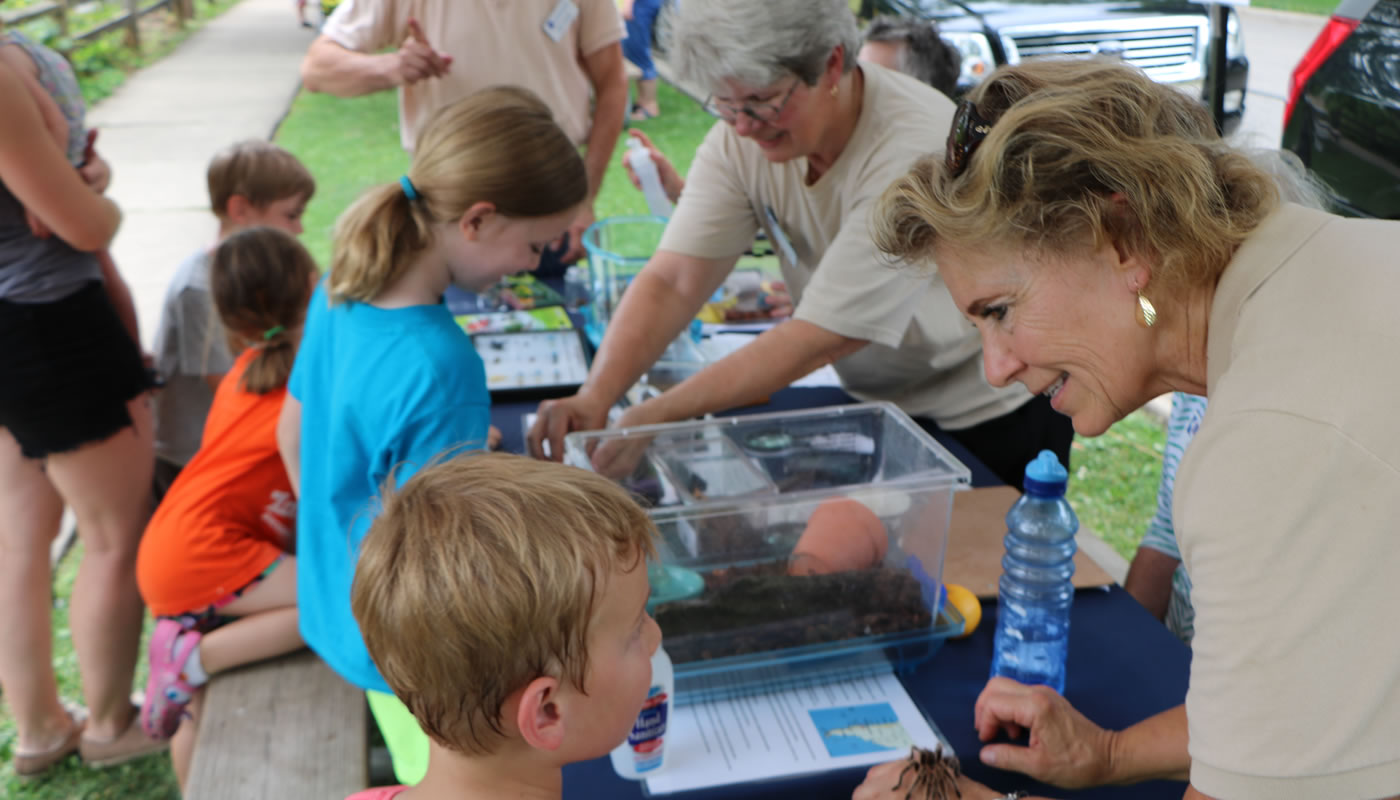 A Master Naturalist shows a spider to a visitor at Insect Fest.