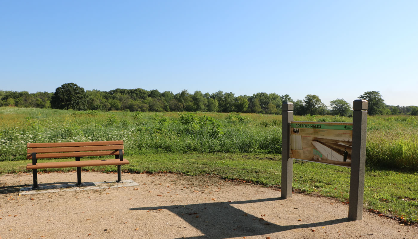 a bench and interpretive sign in front of a prairie at Oak Forest Heritage Preserve.