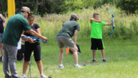 Forest Preserves staff supervising people on an archery range