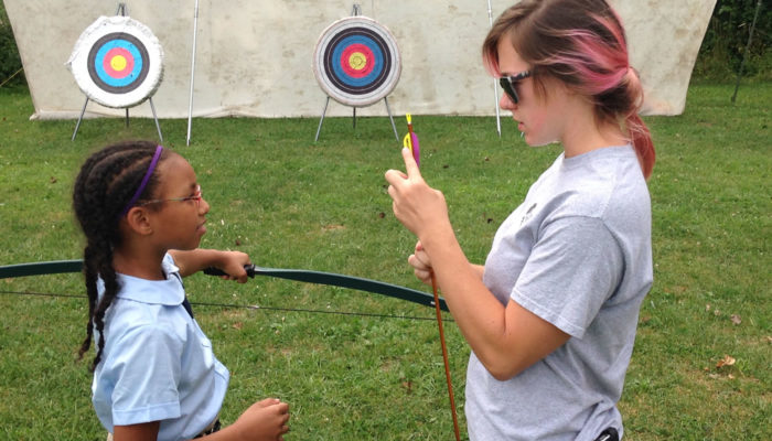 a Forest Preserves staff member teaching a girl the parts of an arrow