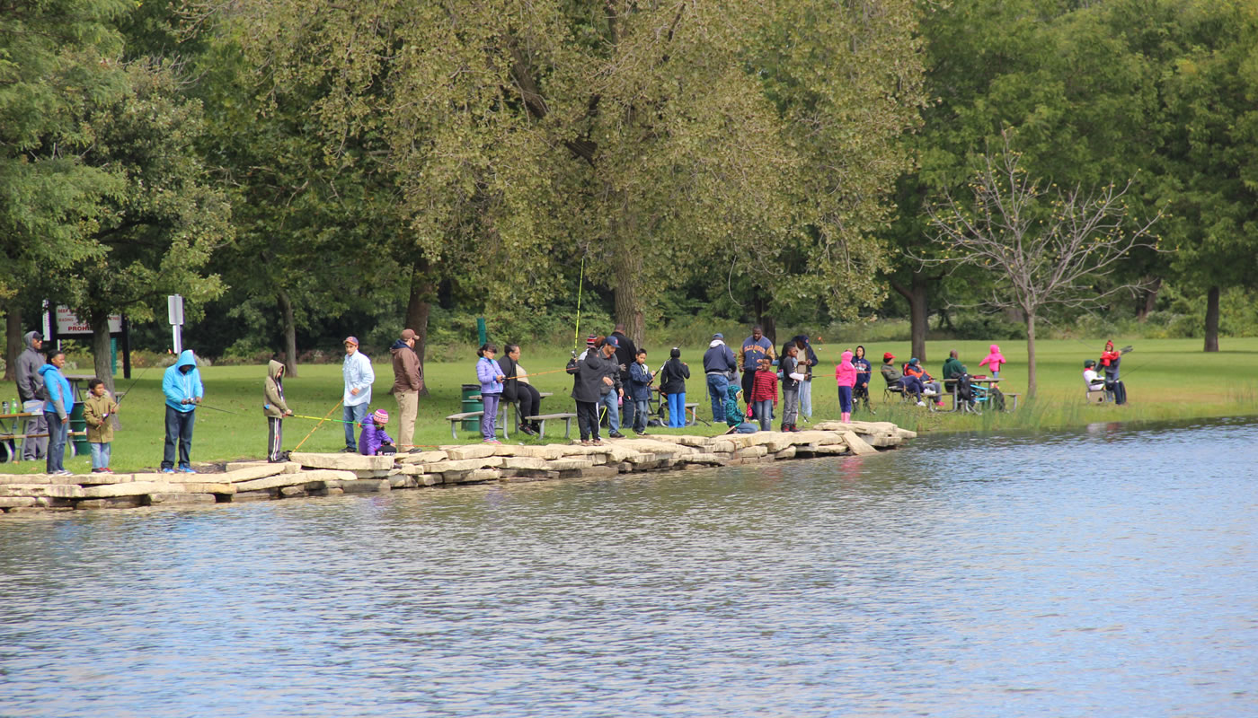 people fishing on the shoreline of a lake during a fishing derby