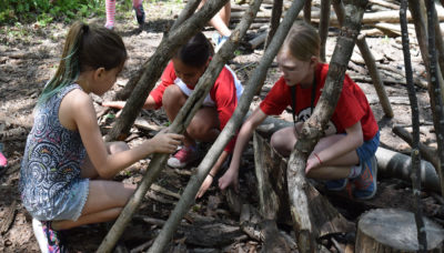 three children building a fort out of logs