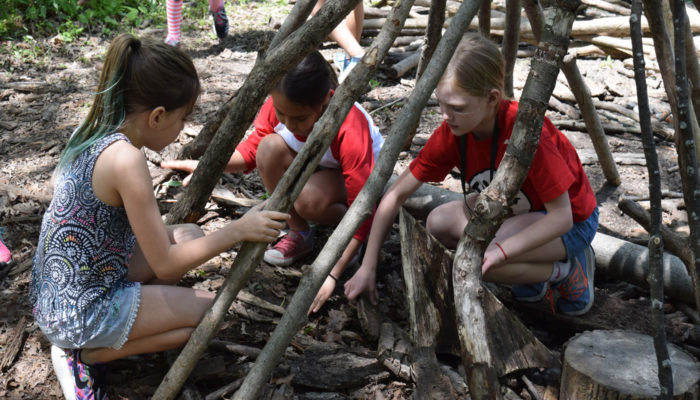 three children building a fort out of logs