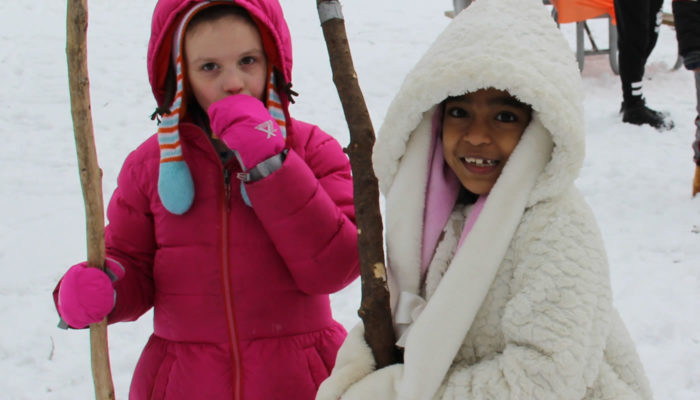 two children with walking sticks in the snow at Whistler Woods