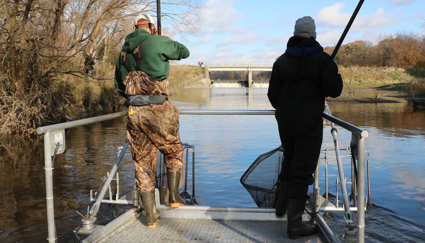 two staff members with nets on the front of a boat near the Busse Reservoir main dam