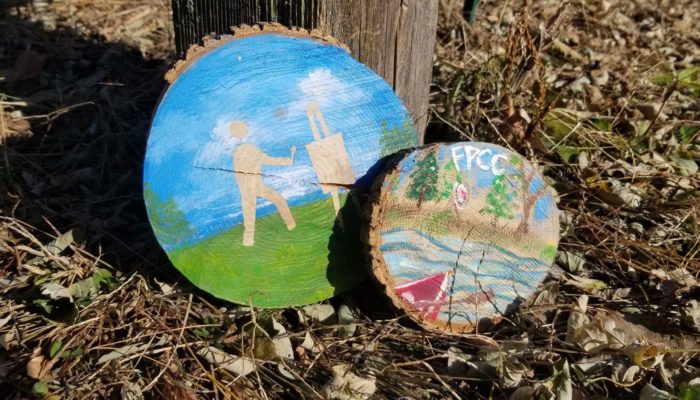 two painted tree trunk slices leaned up against a post at Sand Ridge Nature Center