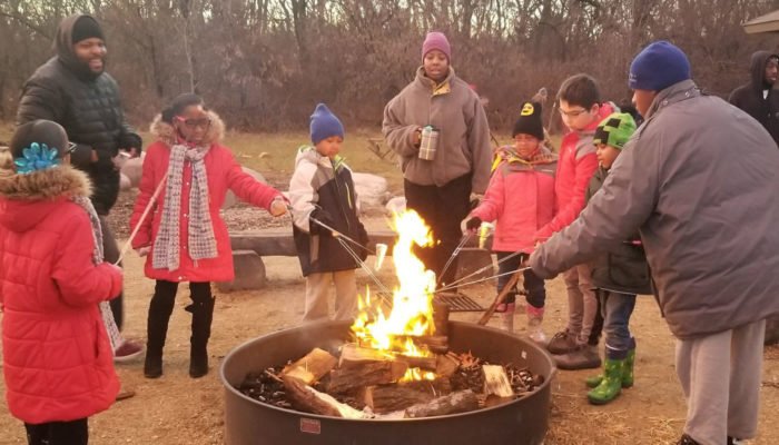 a group cooking over a campfire at Camp Shabbona Woods