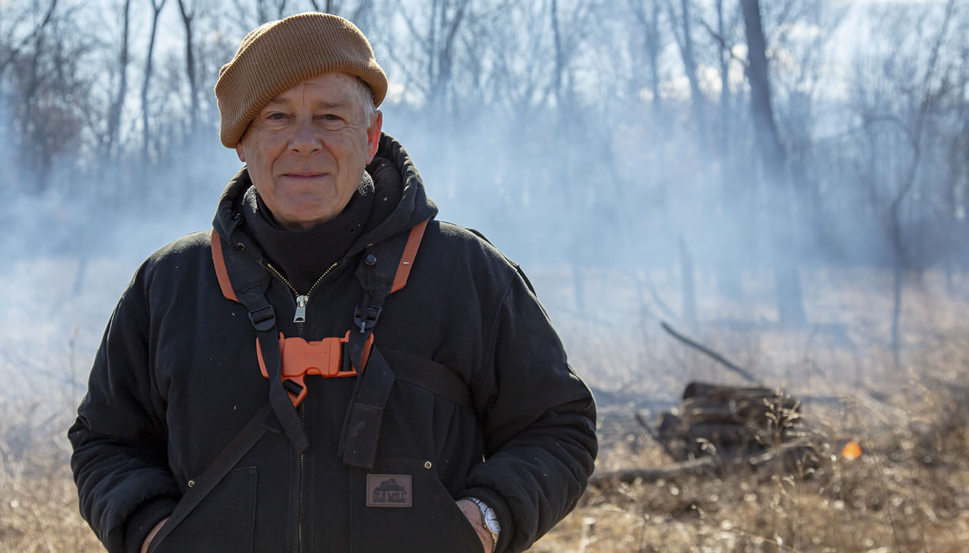 Dennis Kankowske volunteering at Sundown Meadow in front of a brush pile.