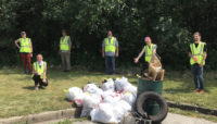 a group of volunteers standing around the trash they collected from the forest preserves