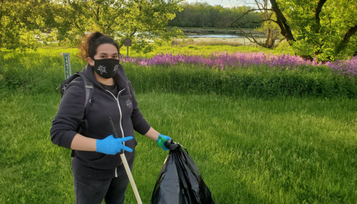 a volunteer picking up trash near a pond in the forest preserves
