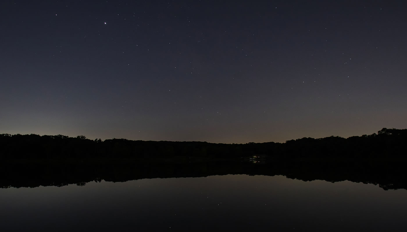view of Maple Lake at night with stars in the sky and reflecting on the water