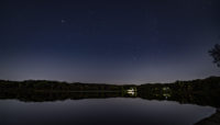 the night sky over Maple Lake with the Maple Lake Boathouse lit up in the background
