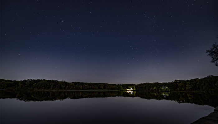 the night sky over Maple Lake with the Maple Lake Boathouse lit up in the background