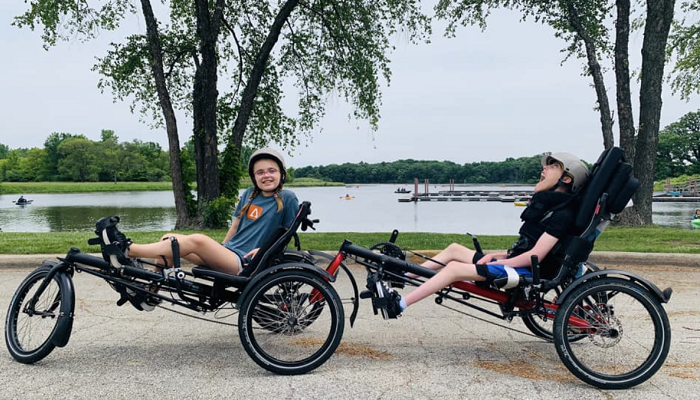 Two youth riding a tandem adaptive bicycle