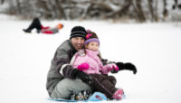 A family sledding at Caldwell Woods.