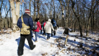 A group hiking in the snow nearby Little Red Schoolhouse Nature Center.