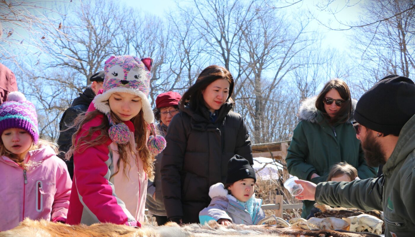 Parents and children learning about different animals next to a display with staff.