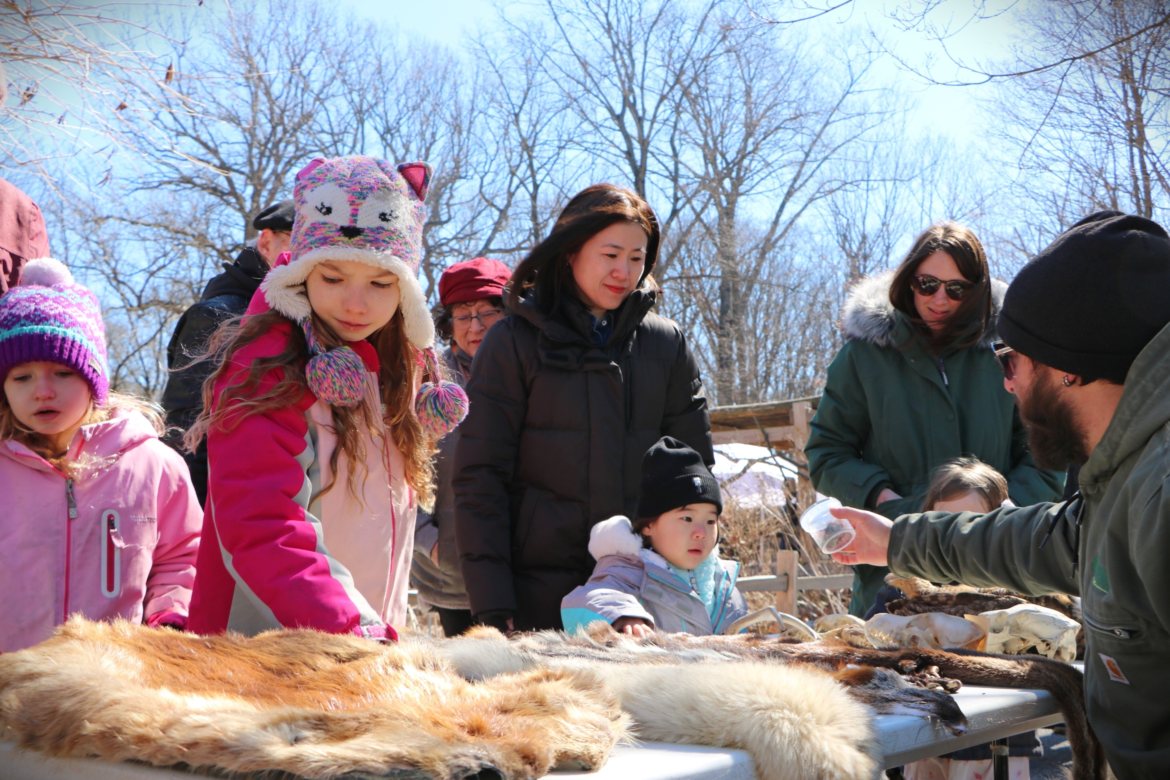 Parents and children learning about different animals next to a display with staff.