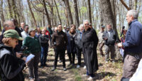 A person presenting to a group of people in a forest setting.