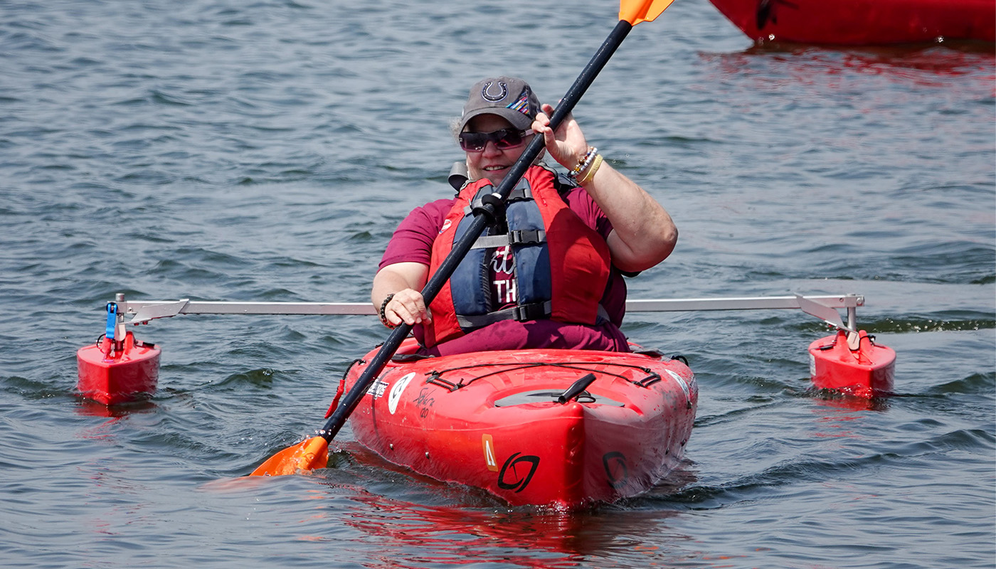 A person paddling in the water using an adaptive kayak.