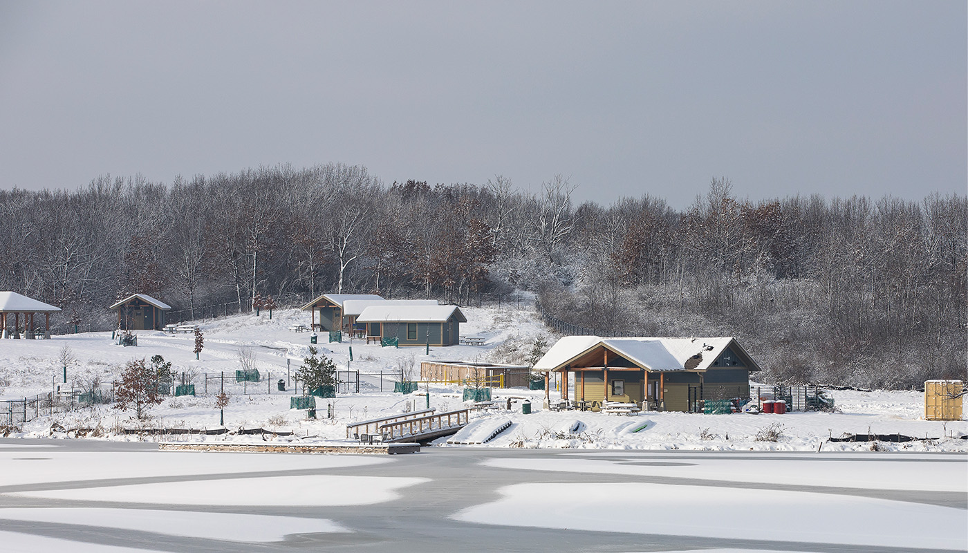 a building covered in snow on the edge of a frozen lake