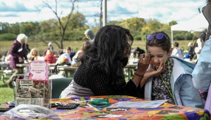 A family face painting at an event.
