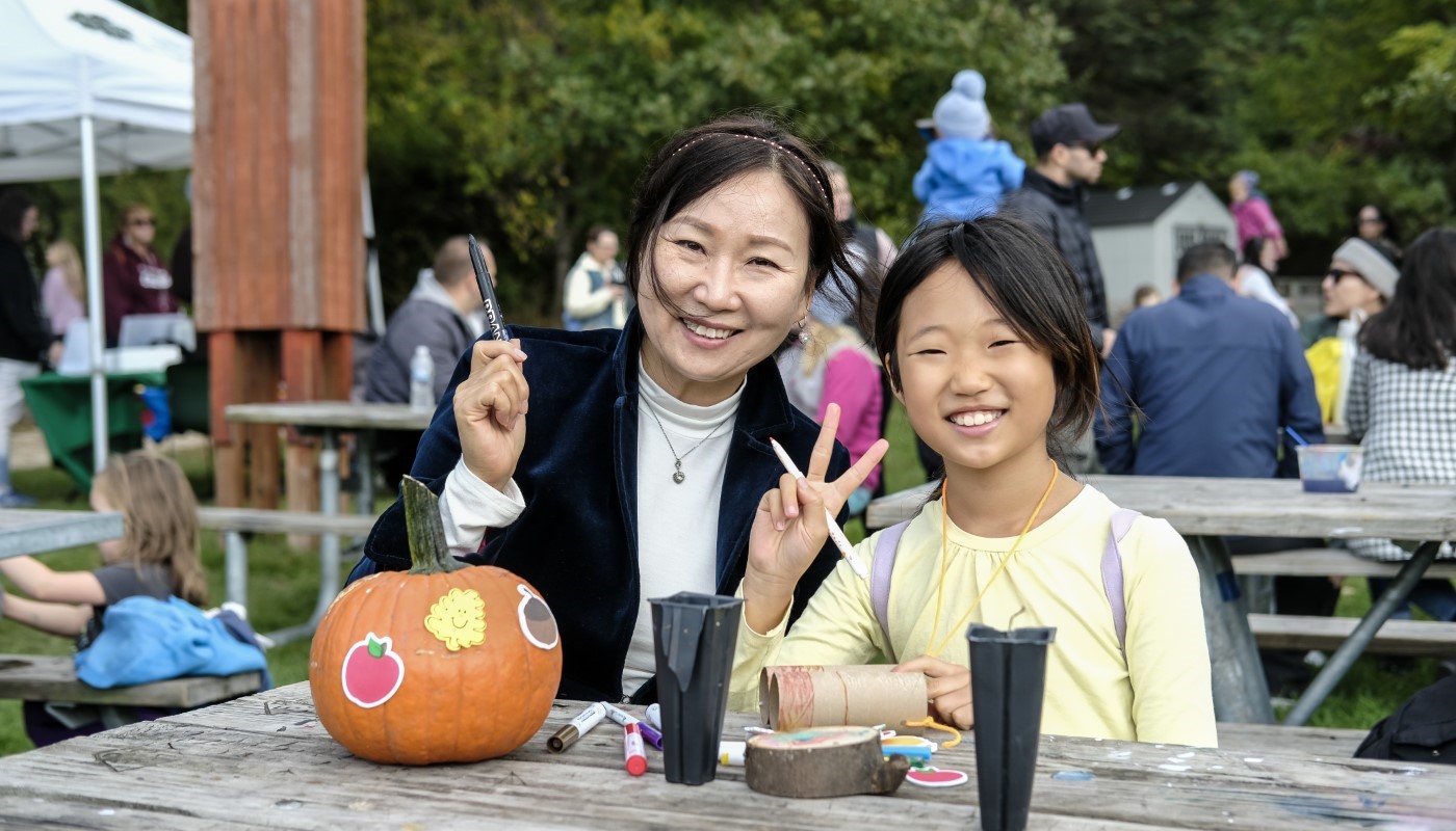 A family painting a pumpkin and crafting at a picnic table.