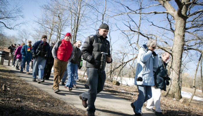 A group of photographers walking along a trail with trees in the background.