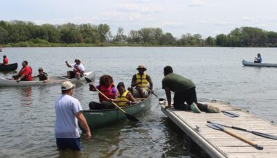 A family docking a canoe in a lake.