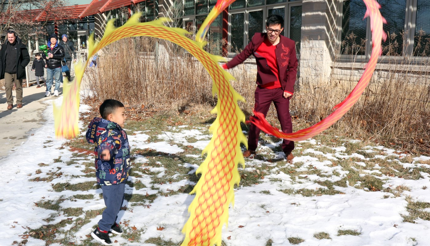 An adult and child participating in a snake dance at a Lunar New Year celebration.