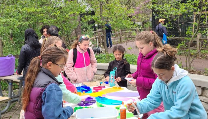 A group of children outside at an Earth Day event making crafts.