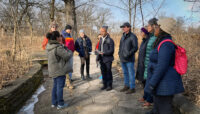 A group of people standing outside on a trail.