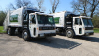 two garbage trucks parked side by side
