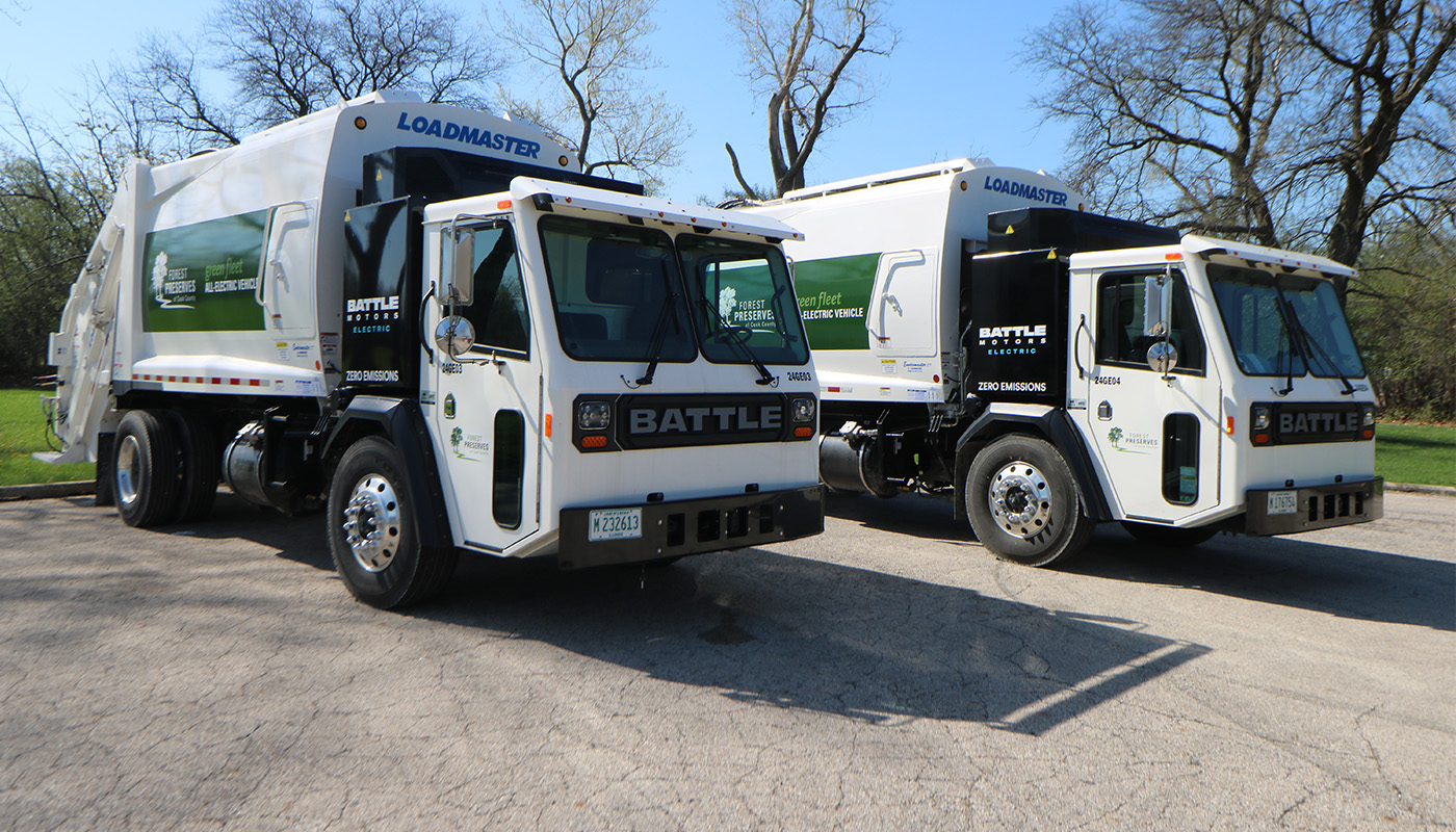 two garbage trucks parked side by side