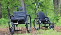 Two all-terrain wheelchairs outdoors.