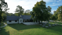 An exterior photo of Thatcher Woods Pavilion, showcasing the building, the grounds and an array of picnic tables.