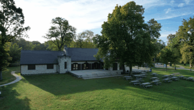 An exterior photo of Thatcher Woods Pavilion, showcasing the building, the grounds and an array of picnic tables.