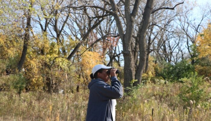 A person birding outdoors in the fall.