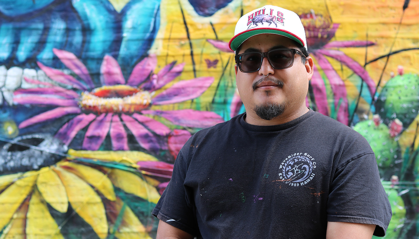 a man posing for a photo in front of a colorful mural