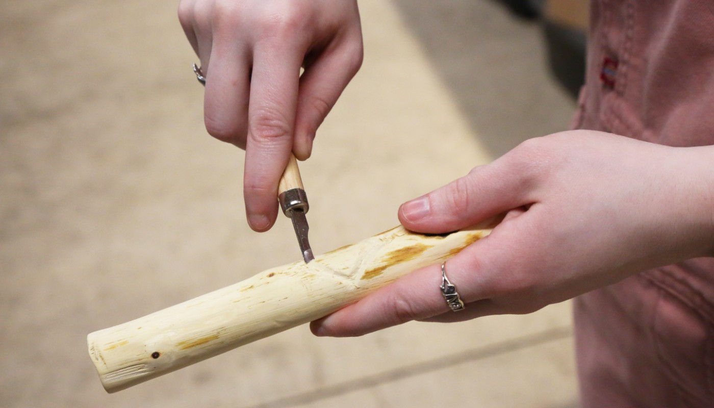 A close-up of a person carving wood at a crafting event.